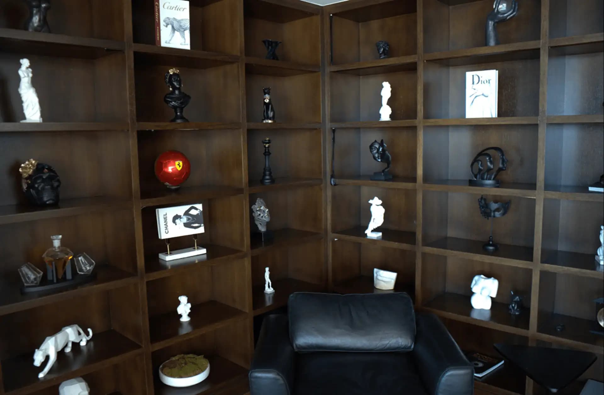 Dust-free dark wood bookshelf with sculptures and fashion books in a luxury Los Angeles home.