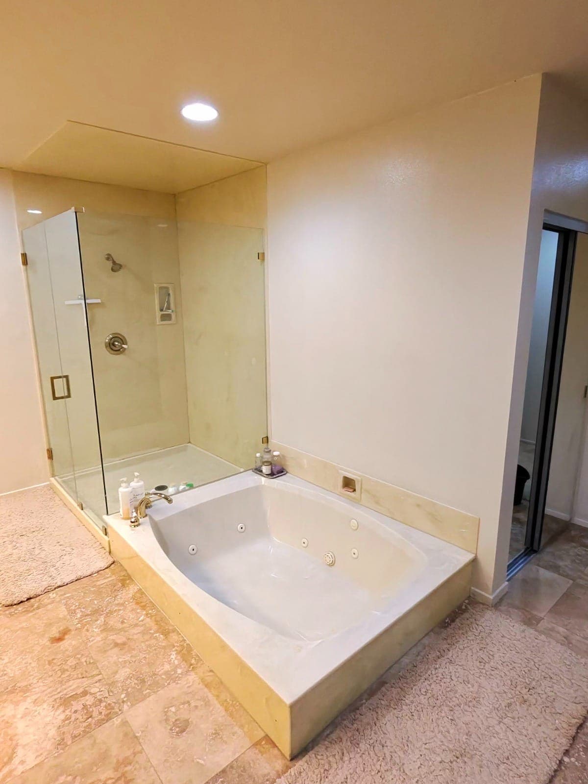 Clean jacuzzi bathtub and glass shower enclosure in a high-end Los Angeles bathroom with marble flooring.