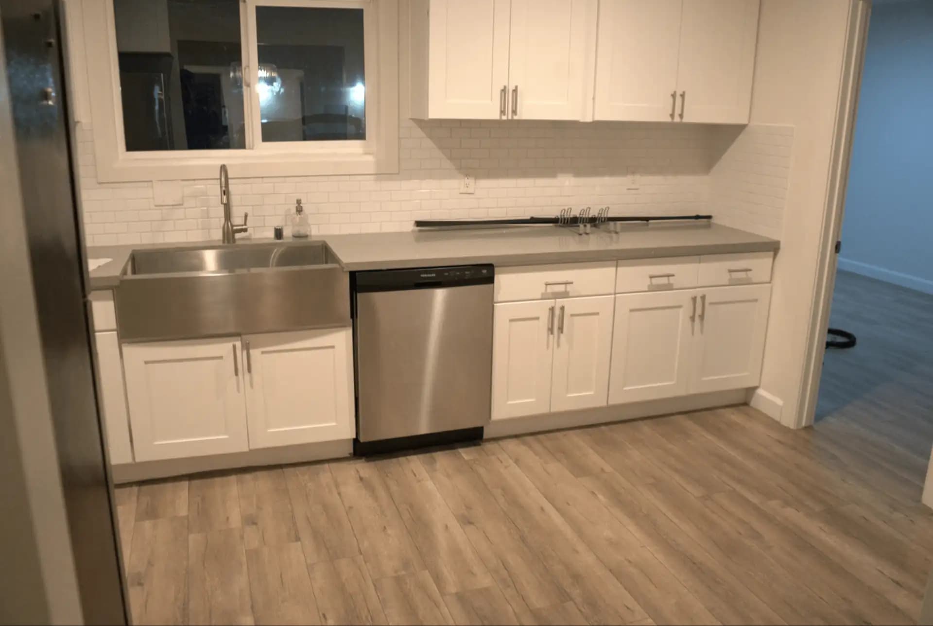 Modern Los Angeles kitchen with white cabinets, stainless steel sink, dishwasher, and spotless wood flooring after a deep clean.