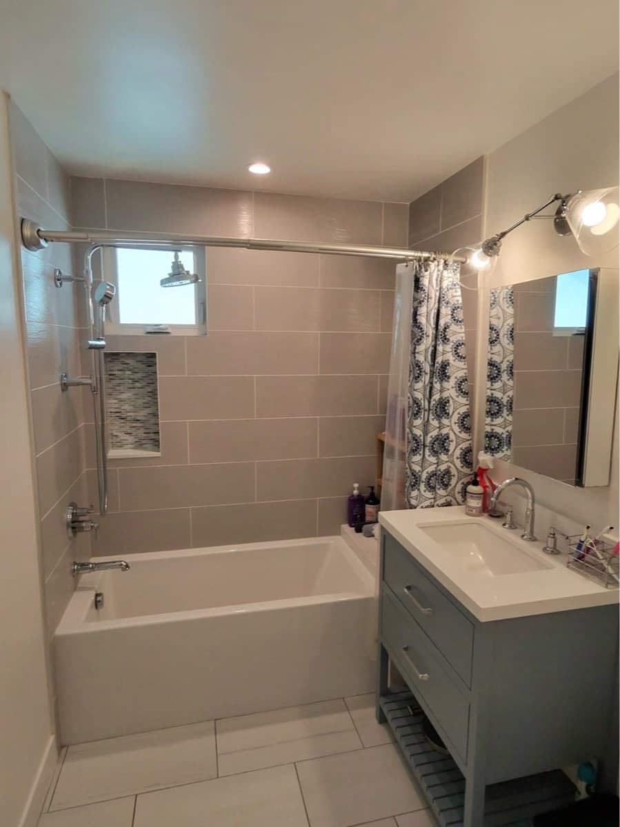 Clean and modern small bathroom with white tub, patterned shower curtain, and vanity sink in Los Angeles.