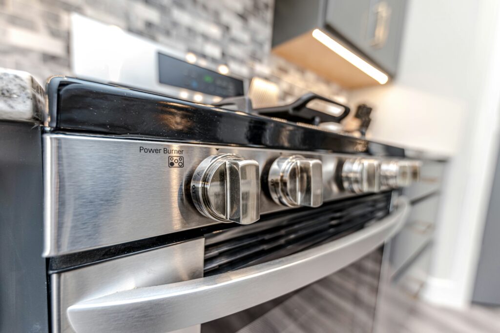 Close-up of a stainless steel stove with clean gas burner knobs in a modern kitchen.