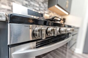 Close-up of a stainless steel stove with clean gas burner knobs in a modern kitchen.