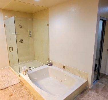 Clean jacuzzi bathtub and glass shower enclosure in a high-end Los Angeles bathroom with marble flooring.