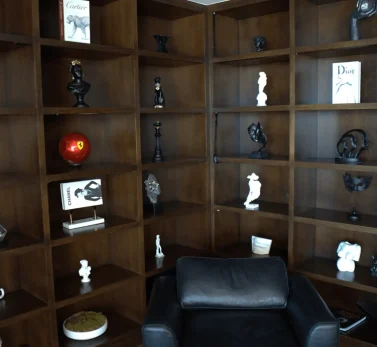 Dust-free dark wood bookshelf with sculptures and fashion books in a luxury Los Angeles home.