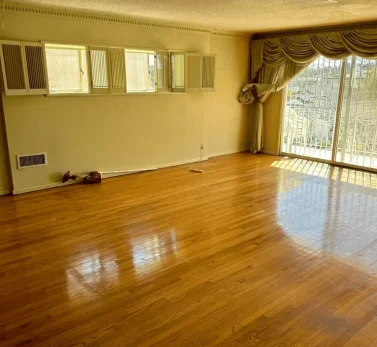 Polished hardwood floor with high-gloss finish in an empty living room with natural light in Los Angeles.